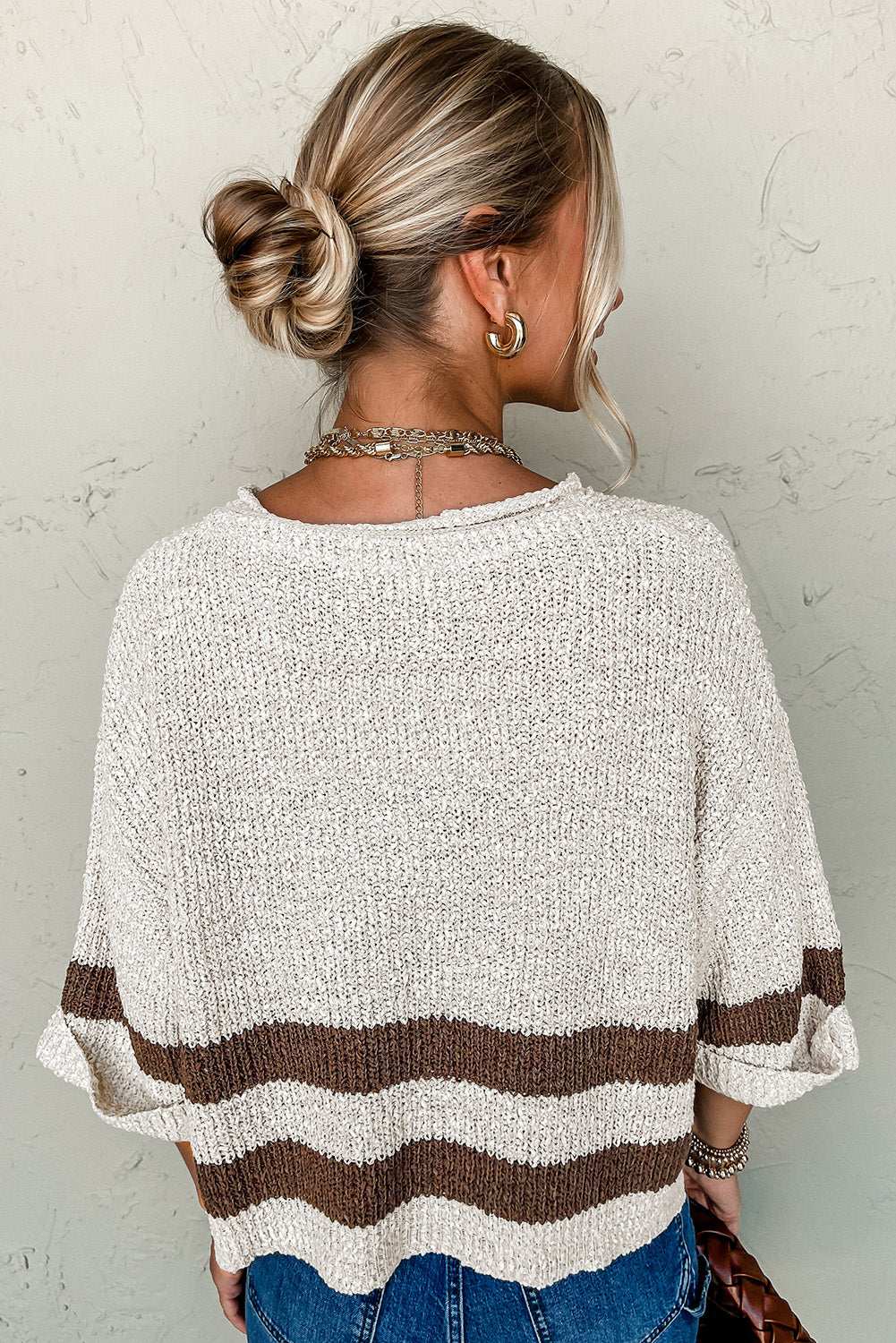 Person wearing a beige and brown striped sweater against a neutral background