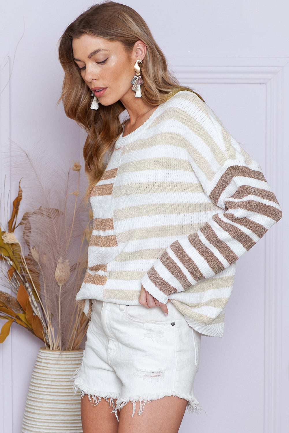 Woman wearing a striped sweater and white shorts against a light background