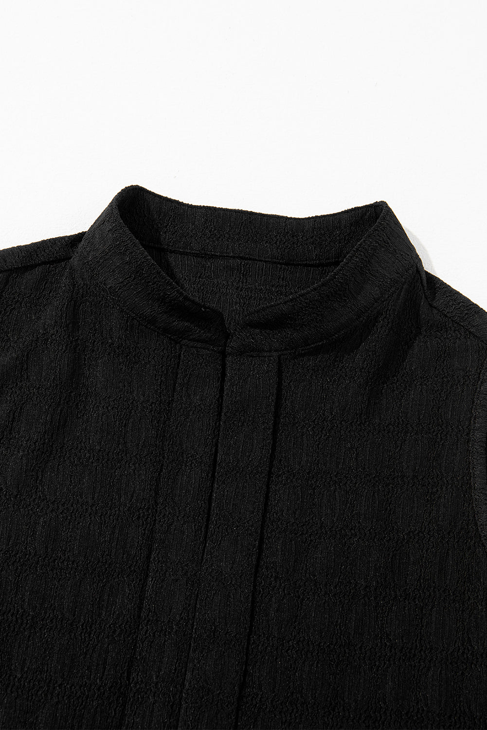 Black sleeveless top with a high neckline on a white background