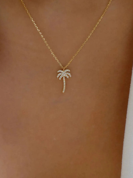 Gold necklace with a palm tree pendant on a person's neck