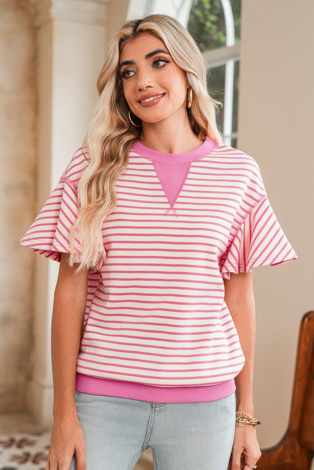 Woman wearing a pink and white striped shirt with a blurred background