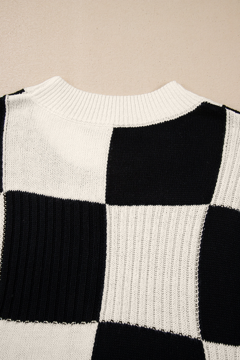 Black and white checkered sweater on a beige background