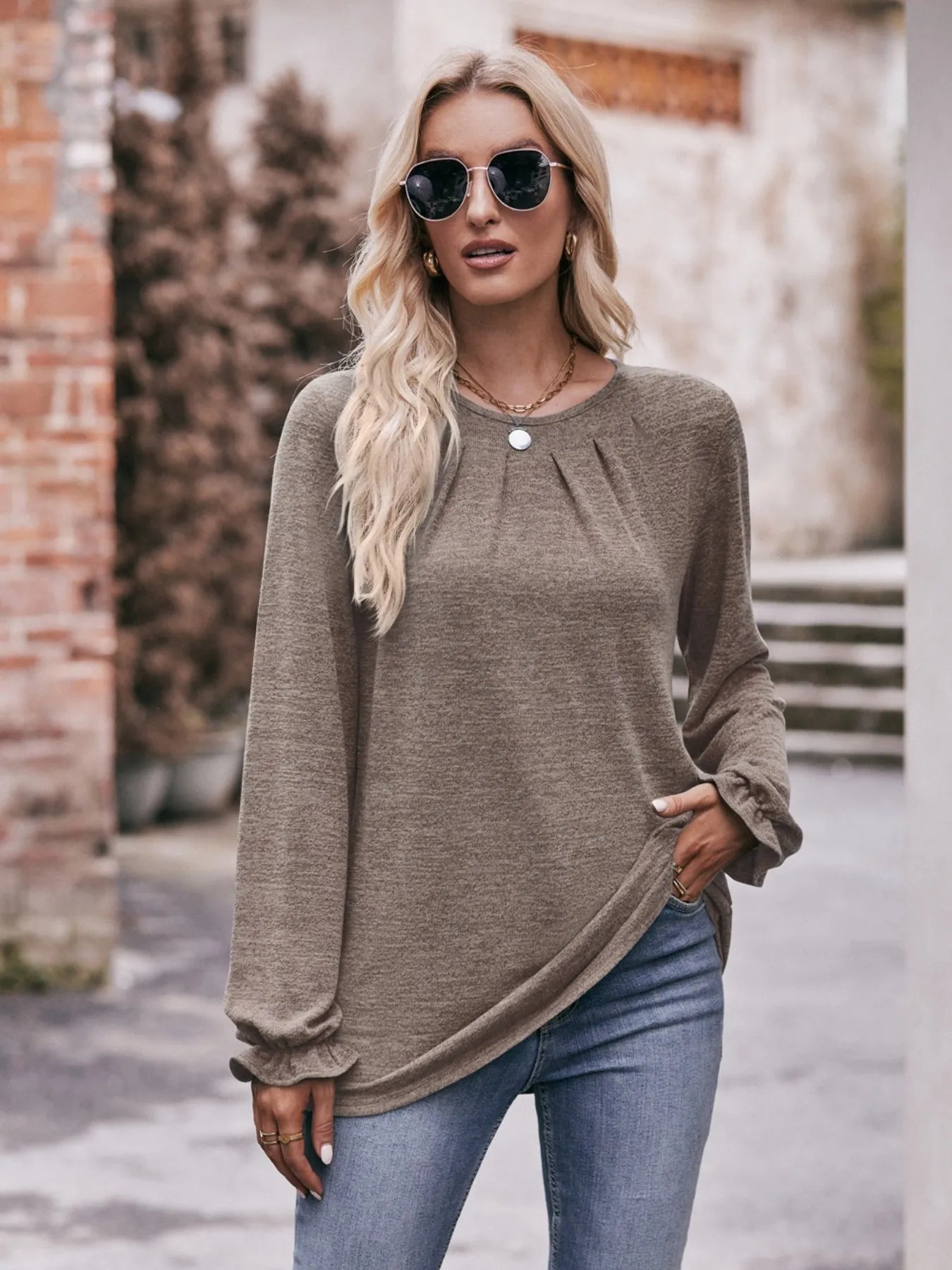 Woman wearing a brown sweater and sunglasses outdoors