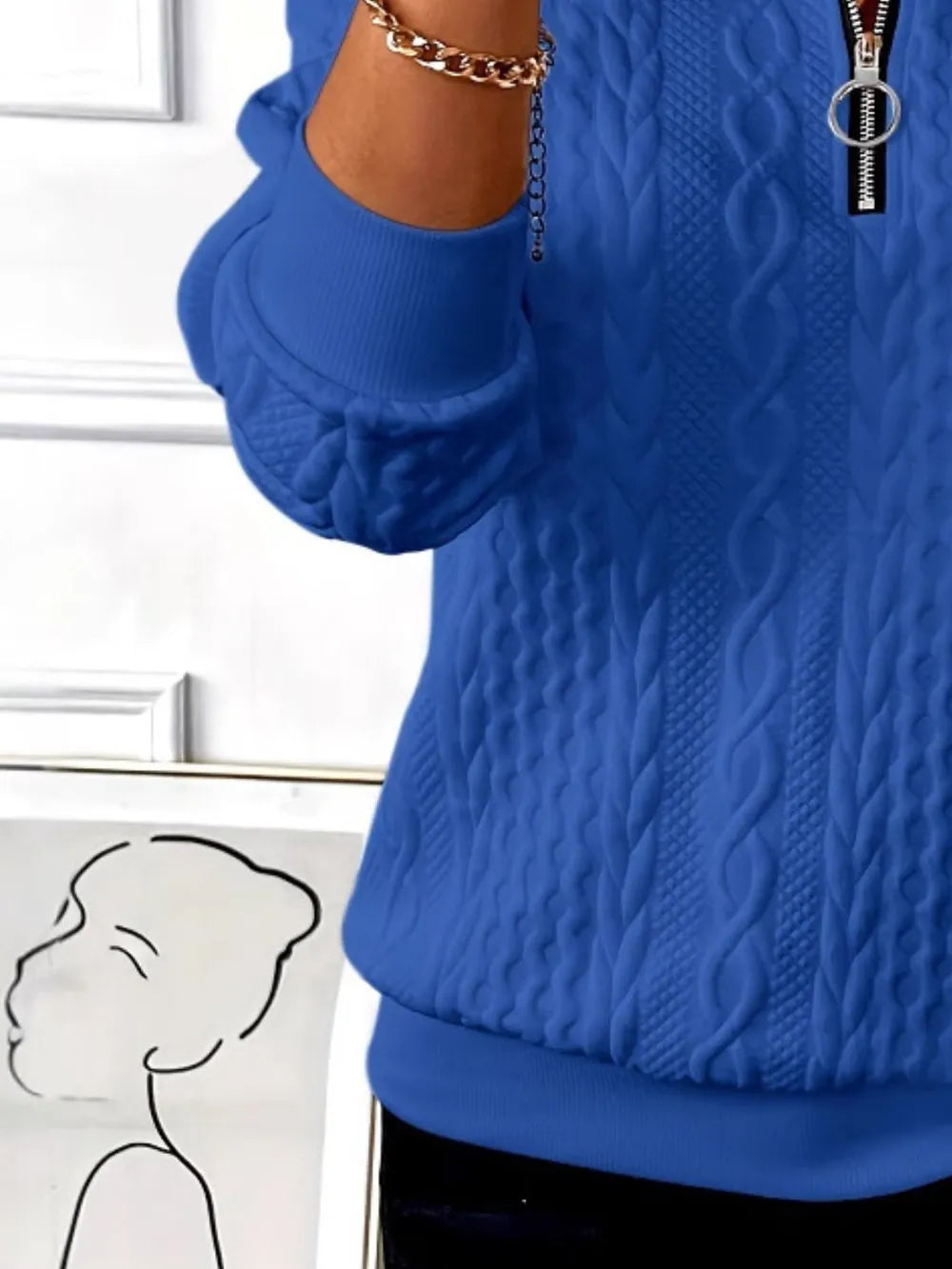 Blue cable knit sweater with a white background