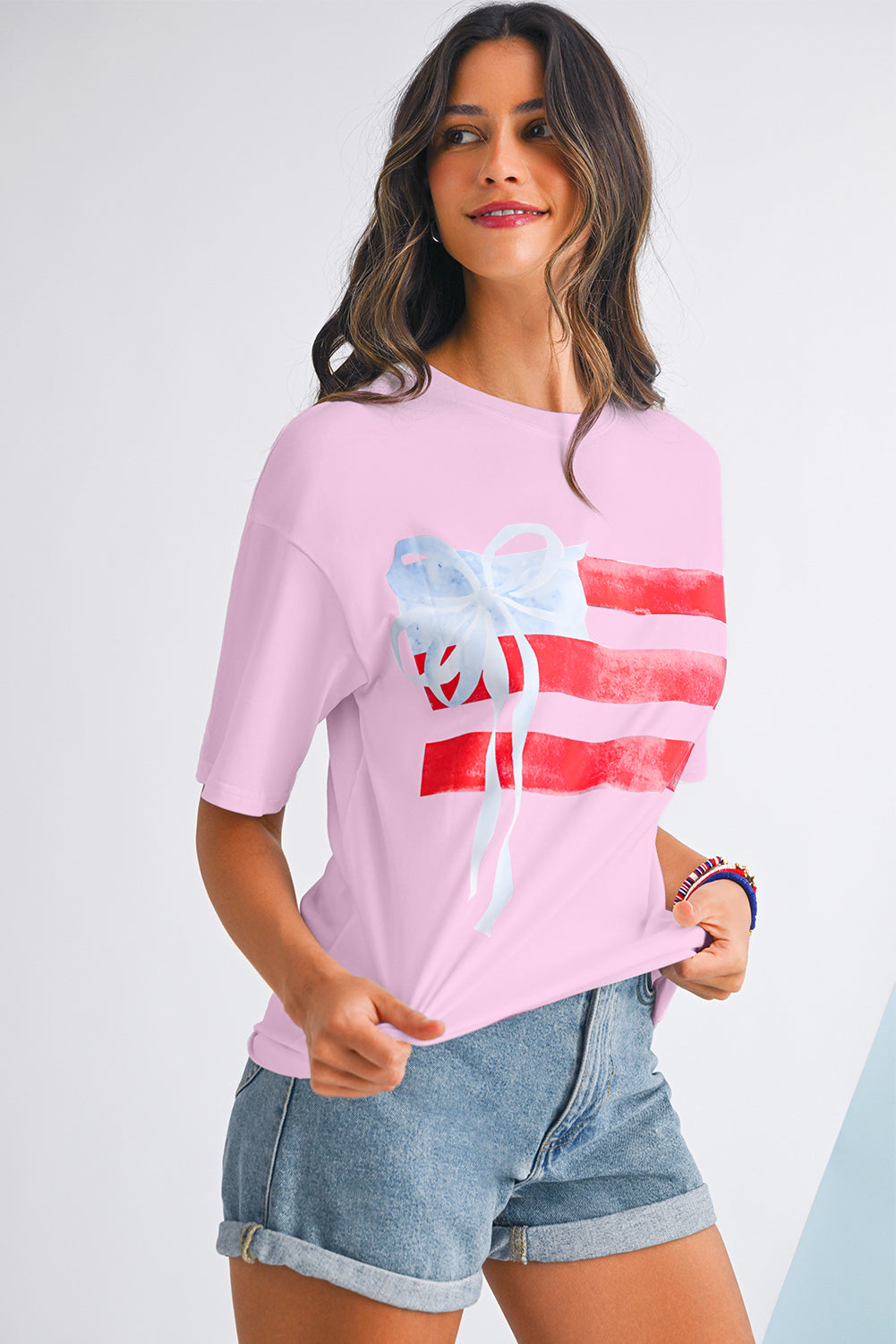 Woman wearing a pink t-shirt with a graphic design on a plain background