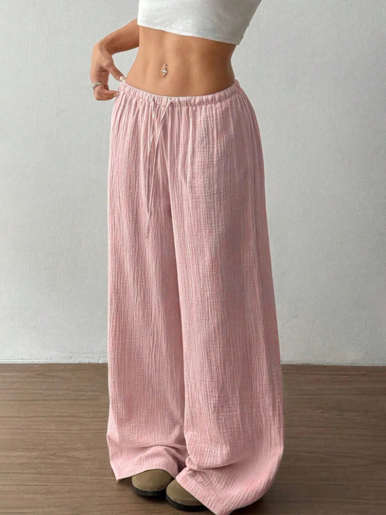 Person wearing light pink wide-leg pants against a plain background