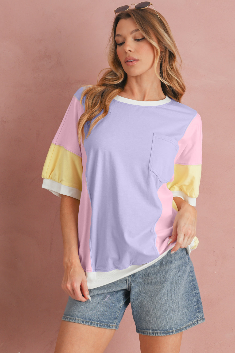 Woman wearing a colorful shirt with a pink, yellow, and purple design on a pink background
