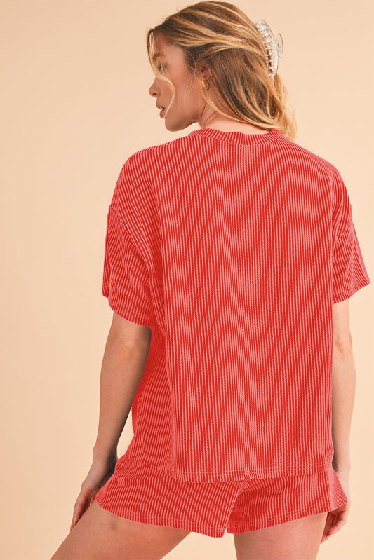 Woman wearing a red ribbed top and shorts set on a beige background