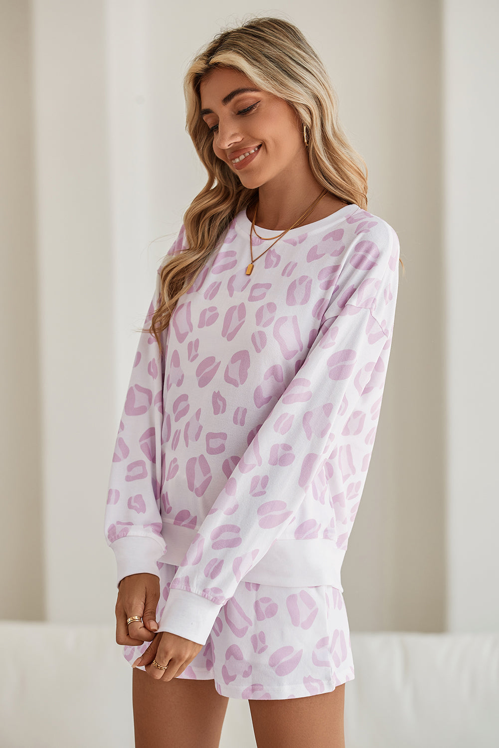 Woman wearing a pink leopard print pajama set against a neutral background
