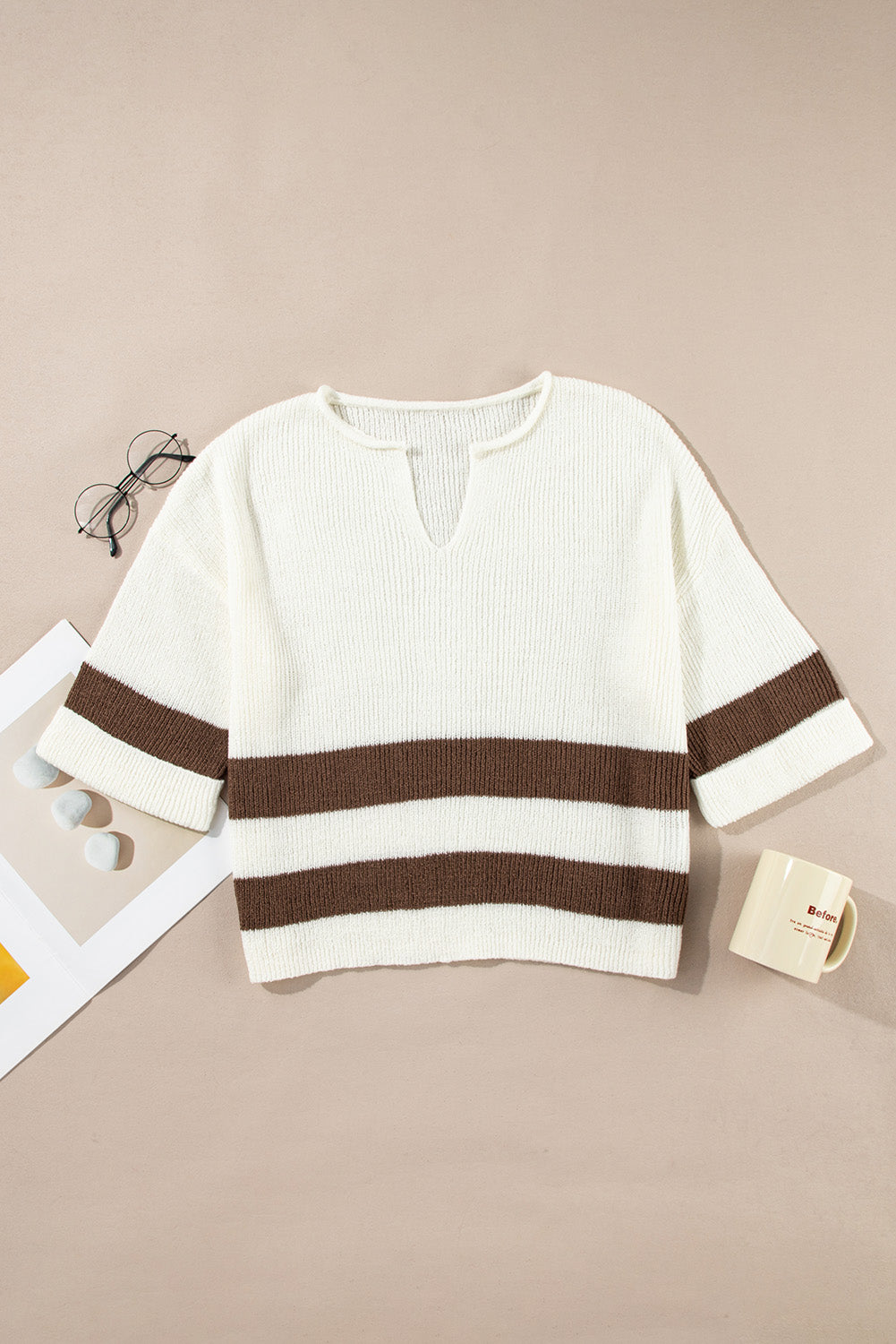 White sweater with brown stripes on a beige surface