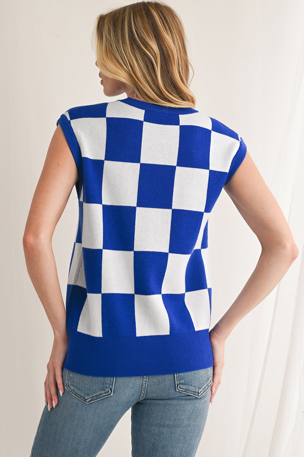 Woman wearing a blue and white checkered sleeveless top against a neutral background