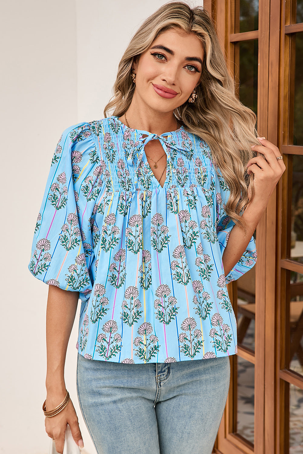 Woman wearing a blue floral blouse with a wooden door in the background