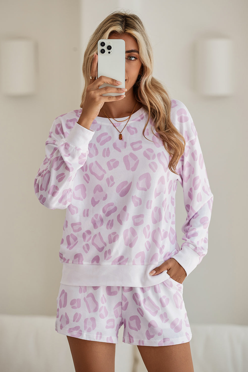 Person wearing a pink leopard print pajama set taking a mirror selfie.