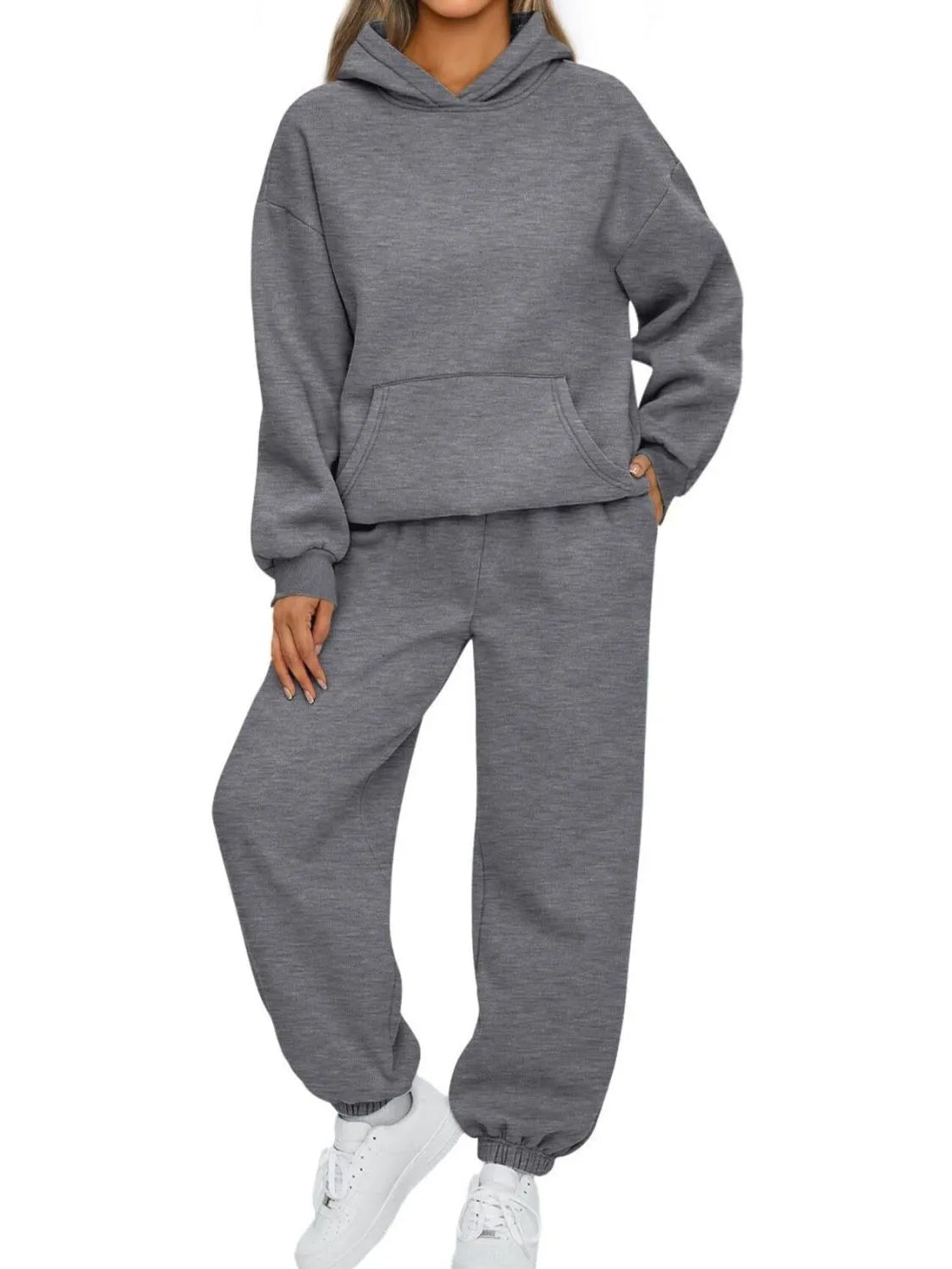 Person wearing a gray hoodie and sweatpants set on a white background