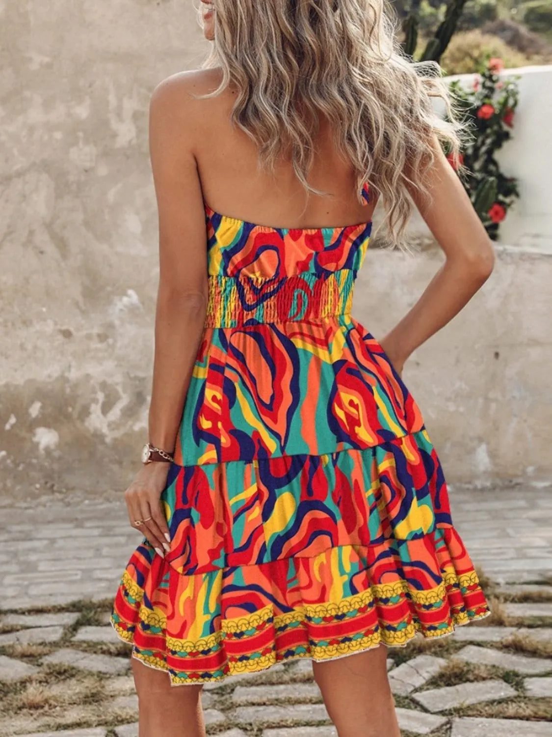 Woman wearing a colorful strapless dress with abstract patterns on a stone path.