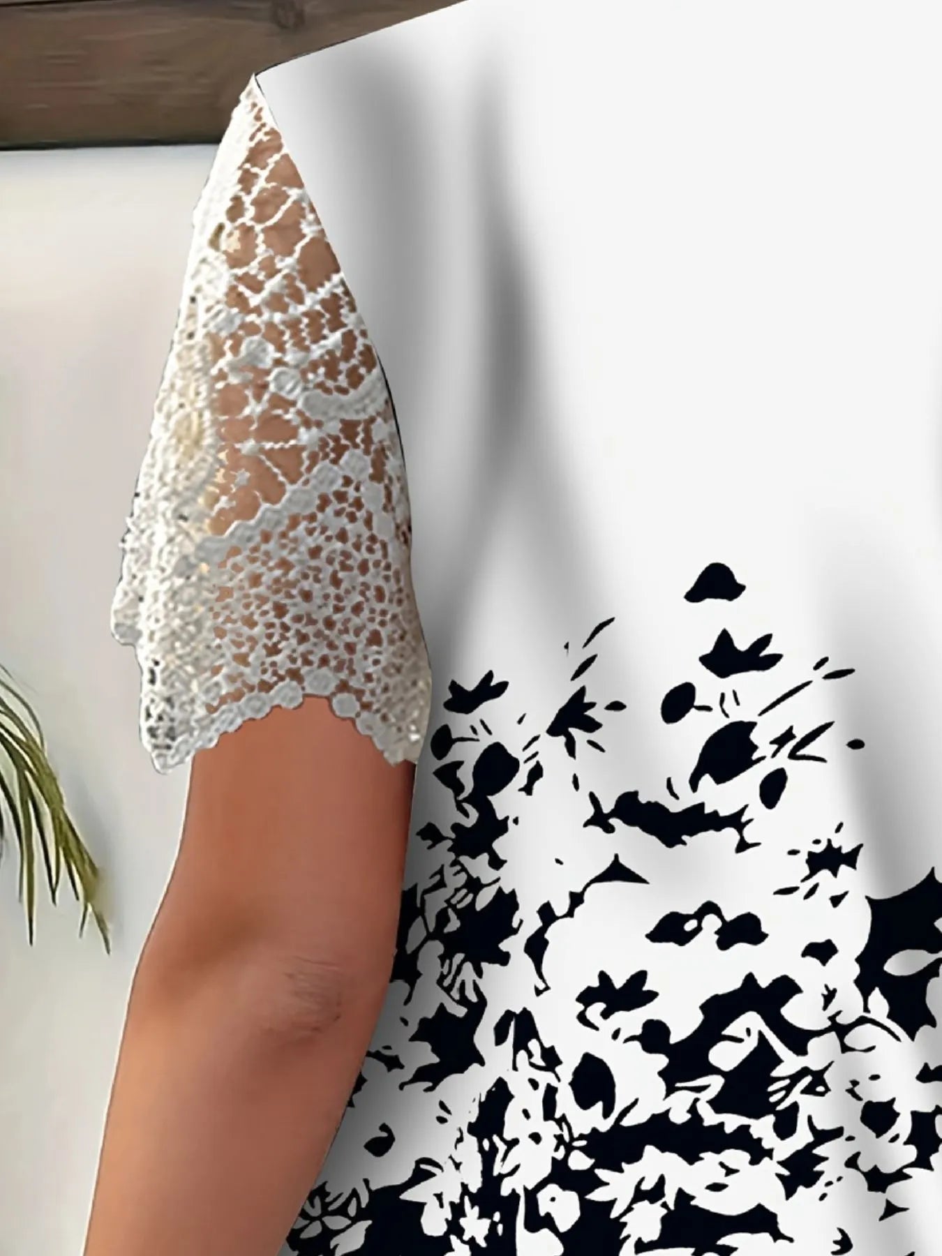 Close-up of a white lace garment on a white background with black floral pattern.