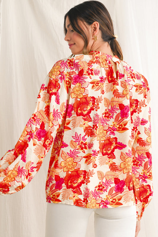 Woman wearing a colorful floral blouse against a plain background