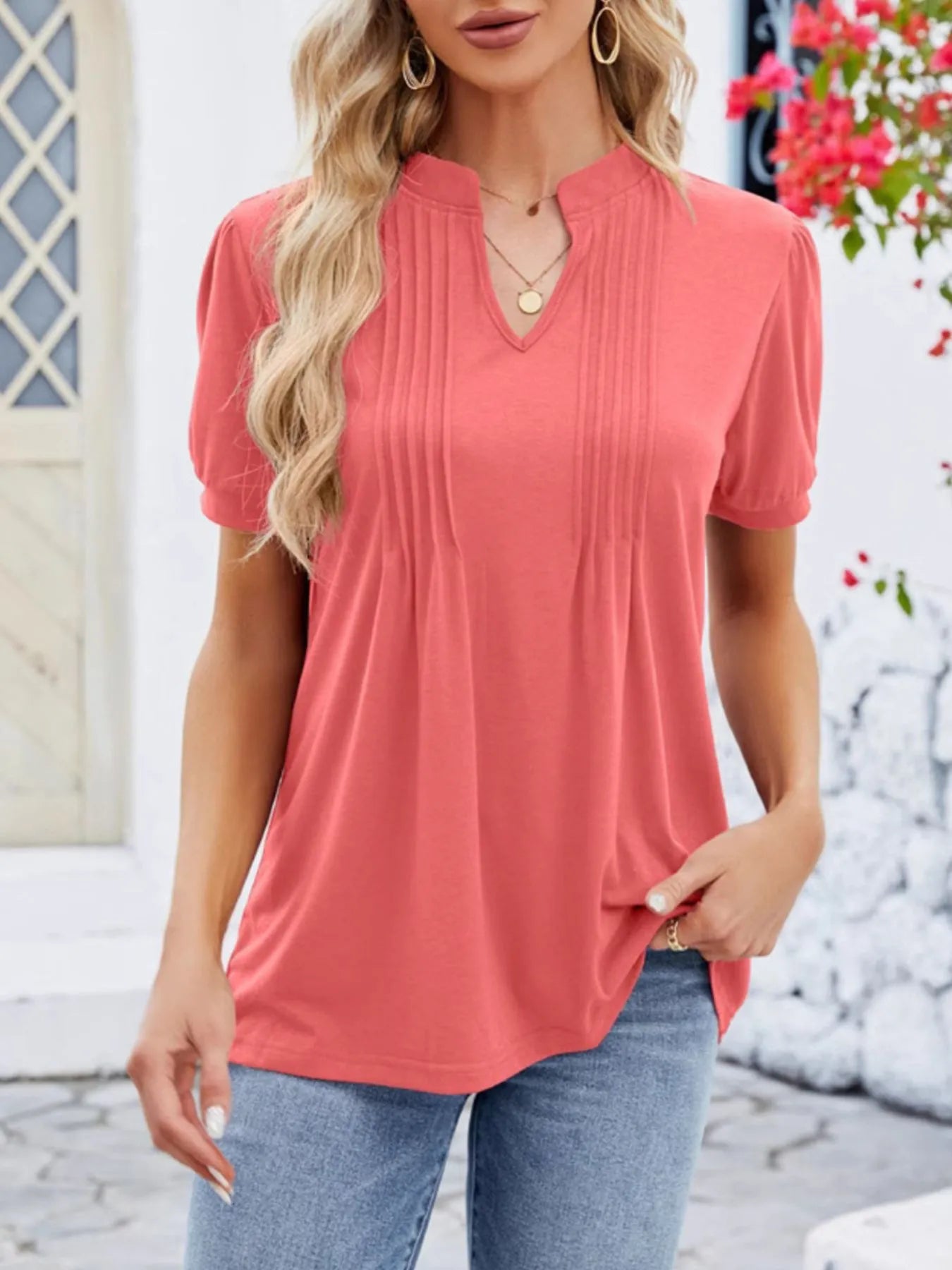 Woman wearing a coral short-sleeve top with a blurred background