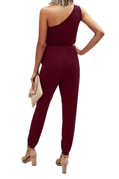 Burgundy one-shoulder jumpsuit worn by a person on a white background