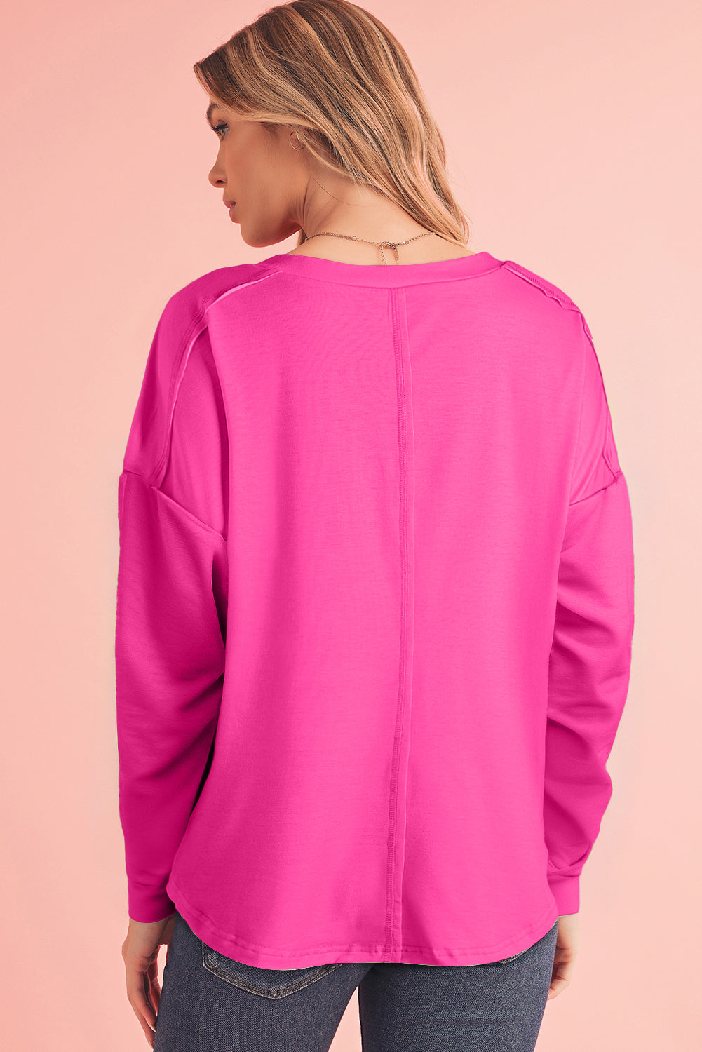 Woman wearing a bright pink long-sleeve top on a pink background