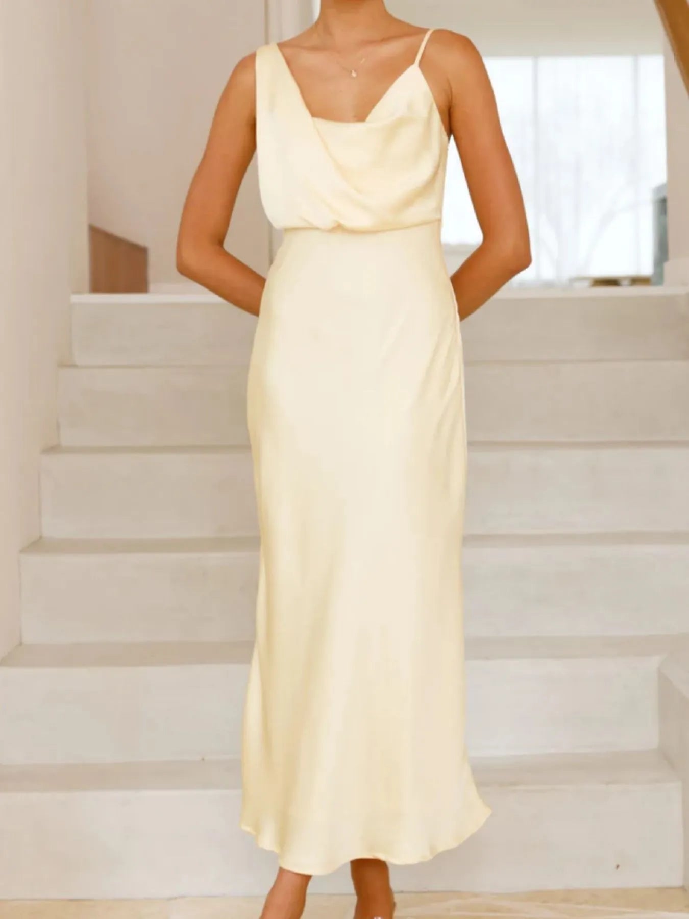 Woman wearing a light yellow dress standing on a staircase.