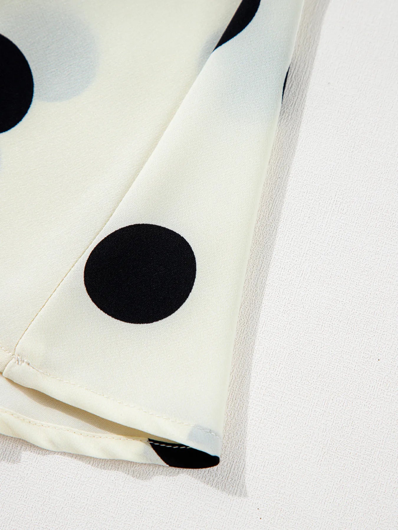 White fabric with black polka dots on a light gray background