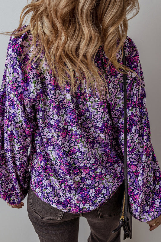 Person wearing a purple floral blouse with a neutral background