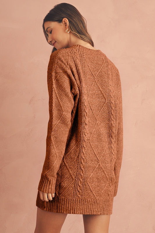 Woman wearing a brown cable knit sweater against a pink background