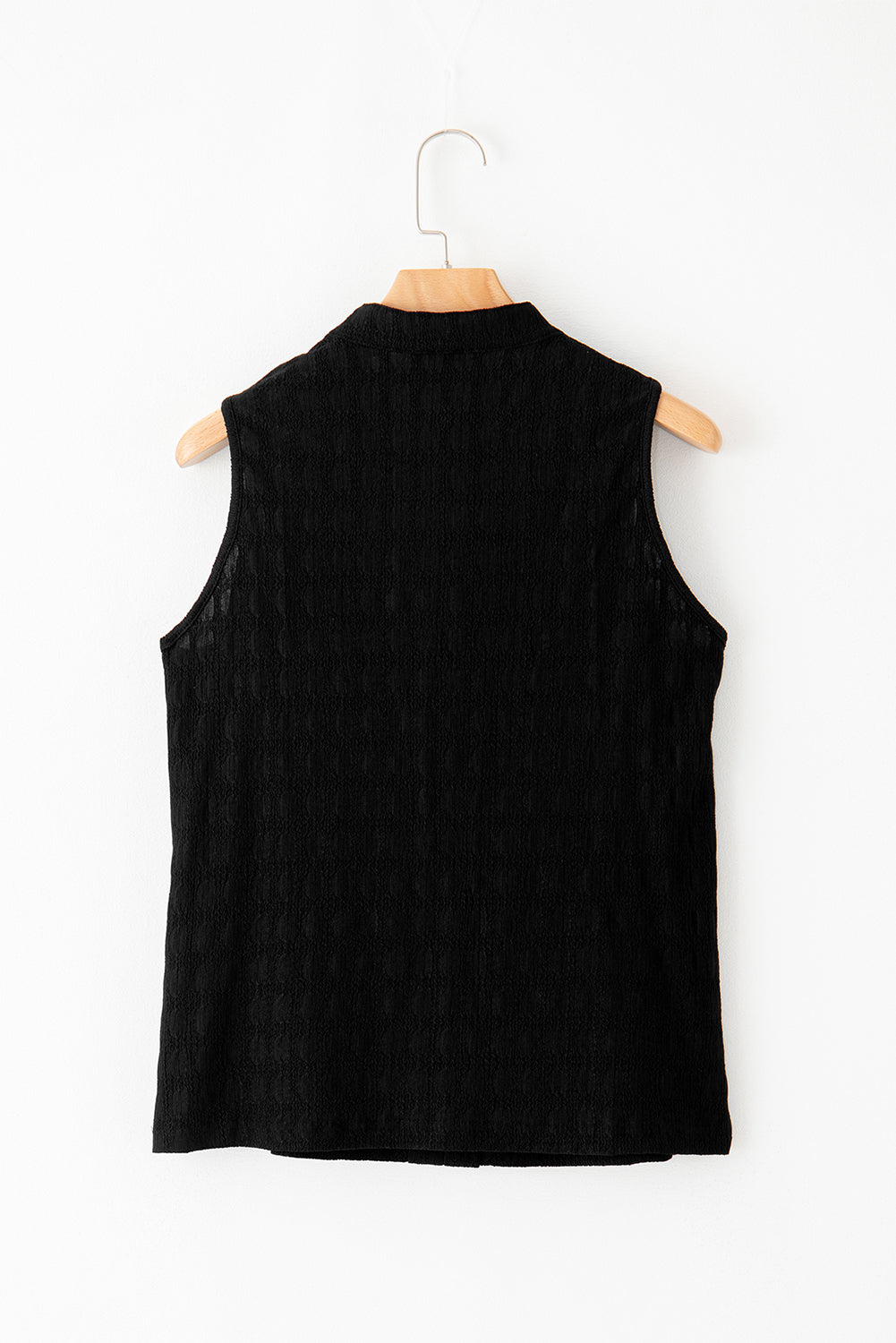Black sleeveless vest on a wooden hanger against a white background