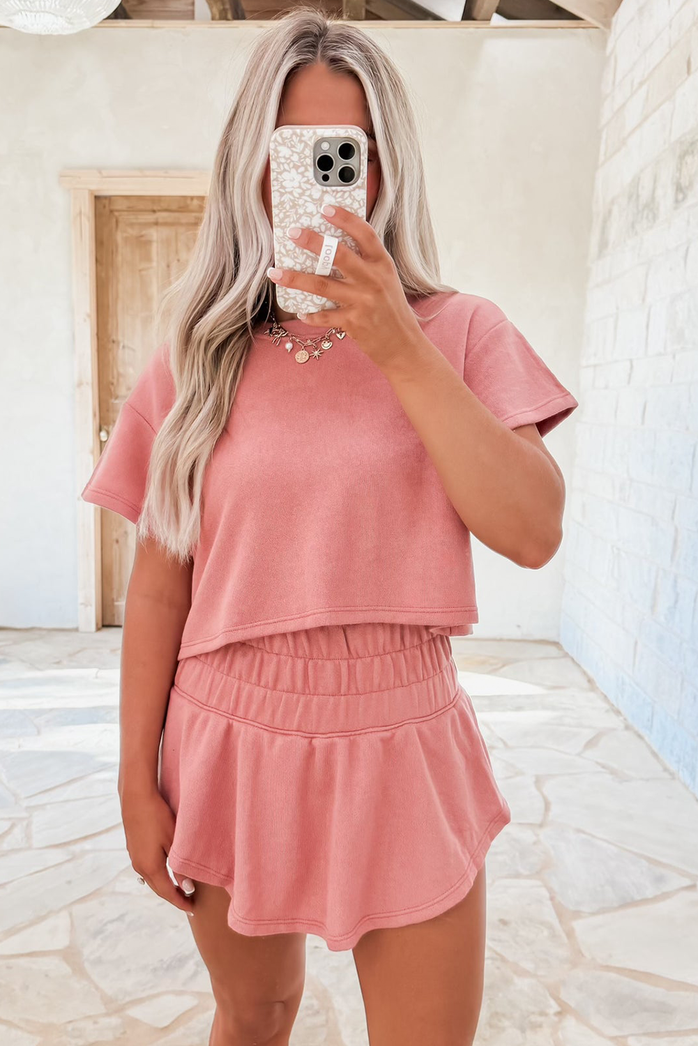 Person wearing a pink outfit taking a mirror selfie.