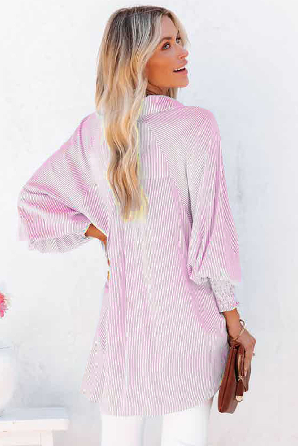 Woman wearing a pink and white striped dress against a white background