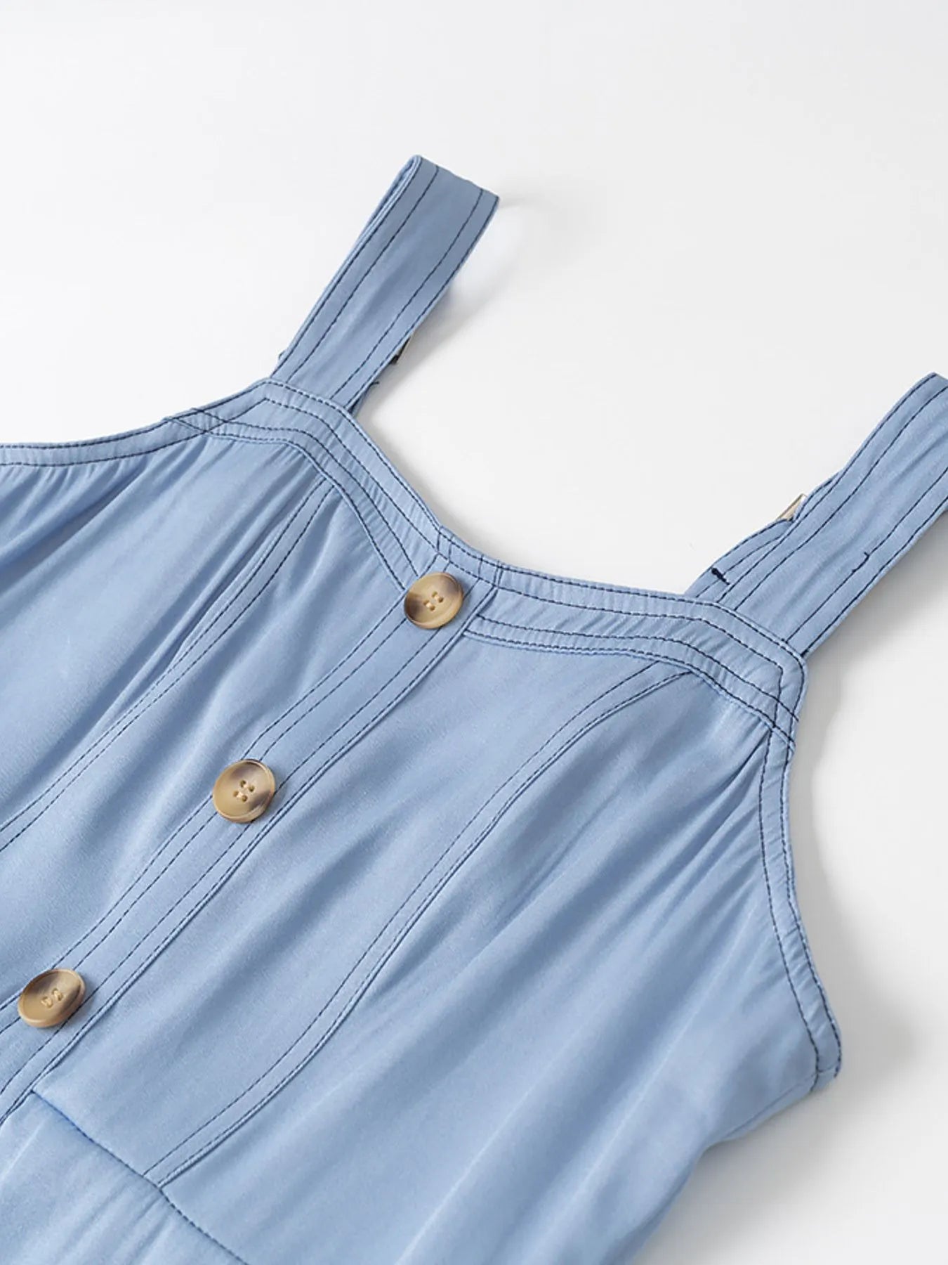 Light blue dress with straps and buttons on a white background