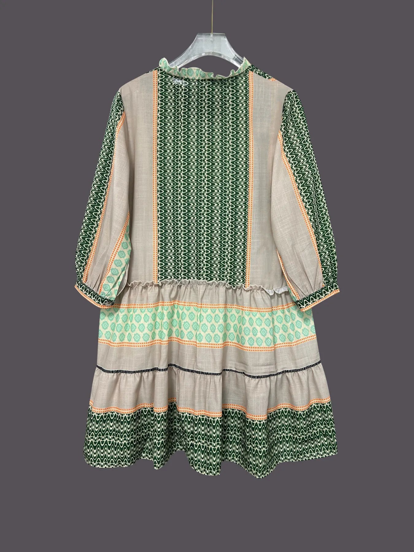Green and beige dress with patterned design on a gray background