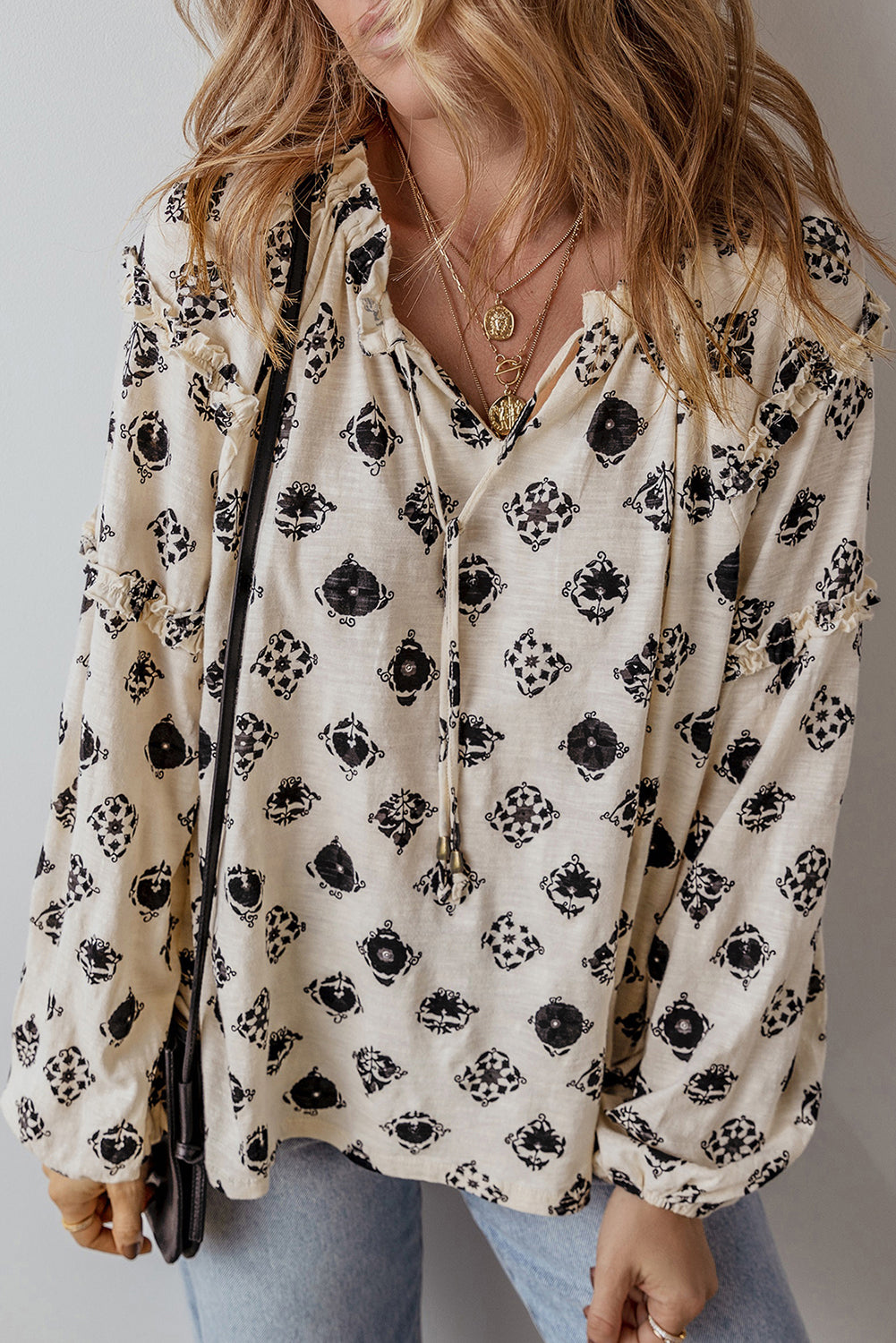 Person wearing a floral blouse with black patterns on a plain background