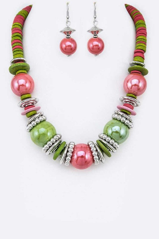 Necklace and earrings with pink and green beads on a white background