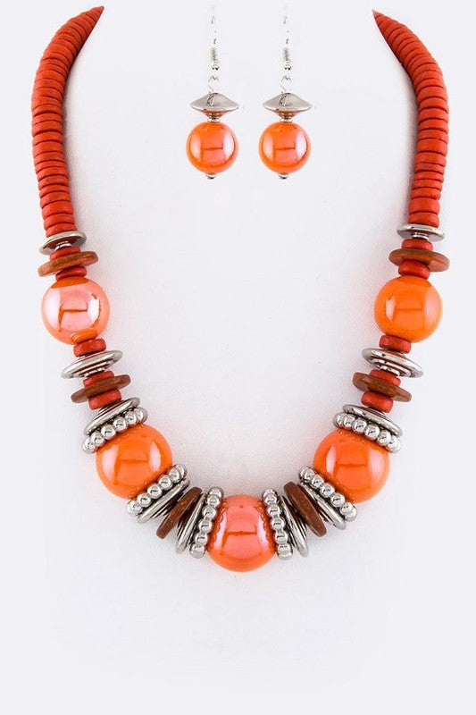 Necklace and earrings set with orange beads and silver accents on a white background