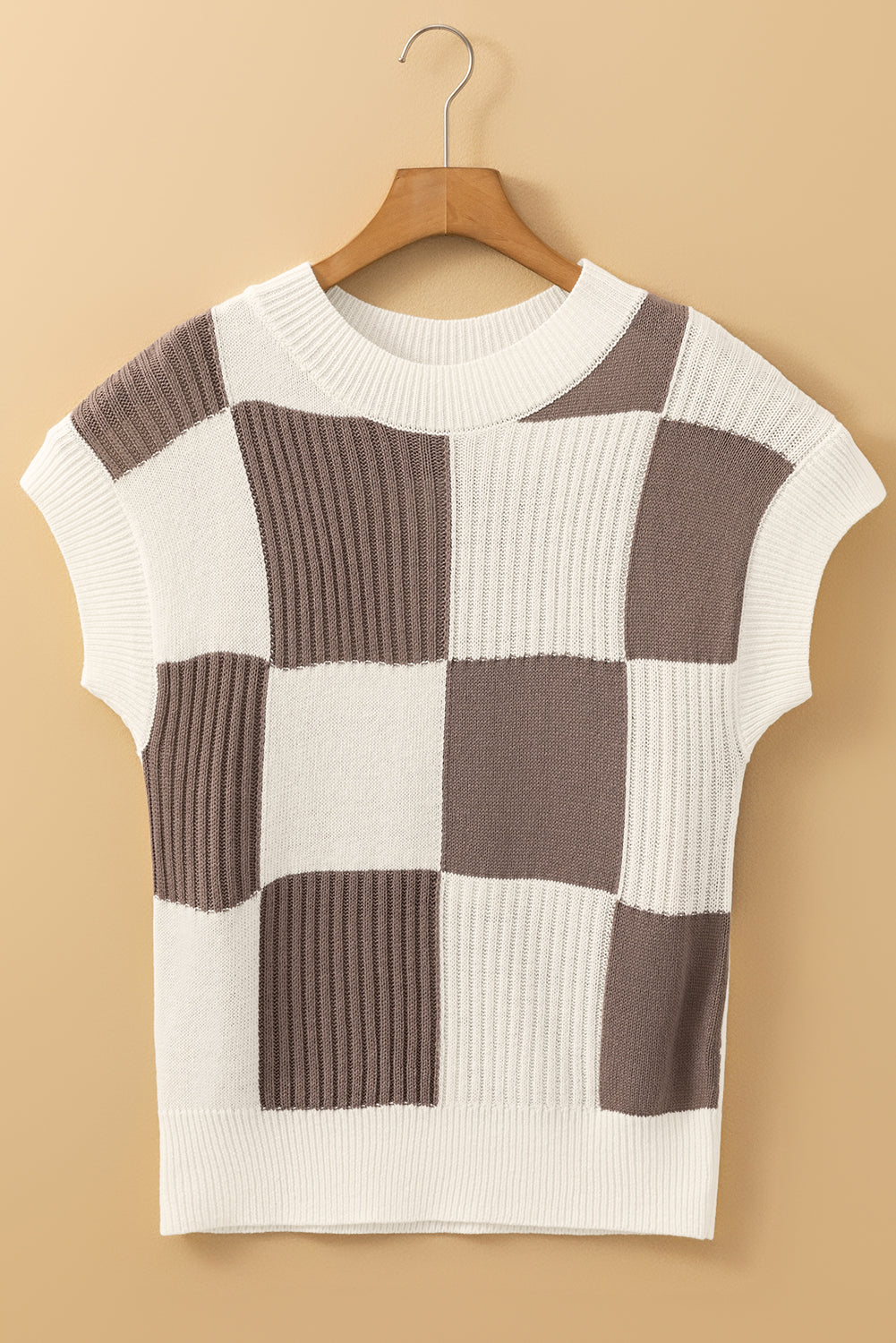 Checkered sweater on a hanger against a beige background