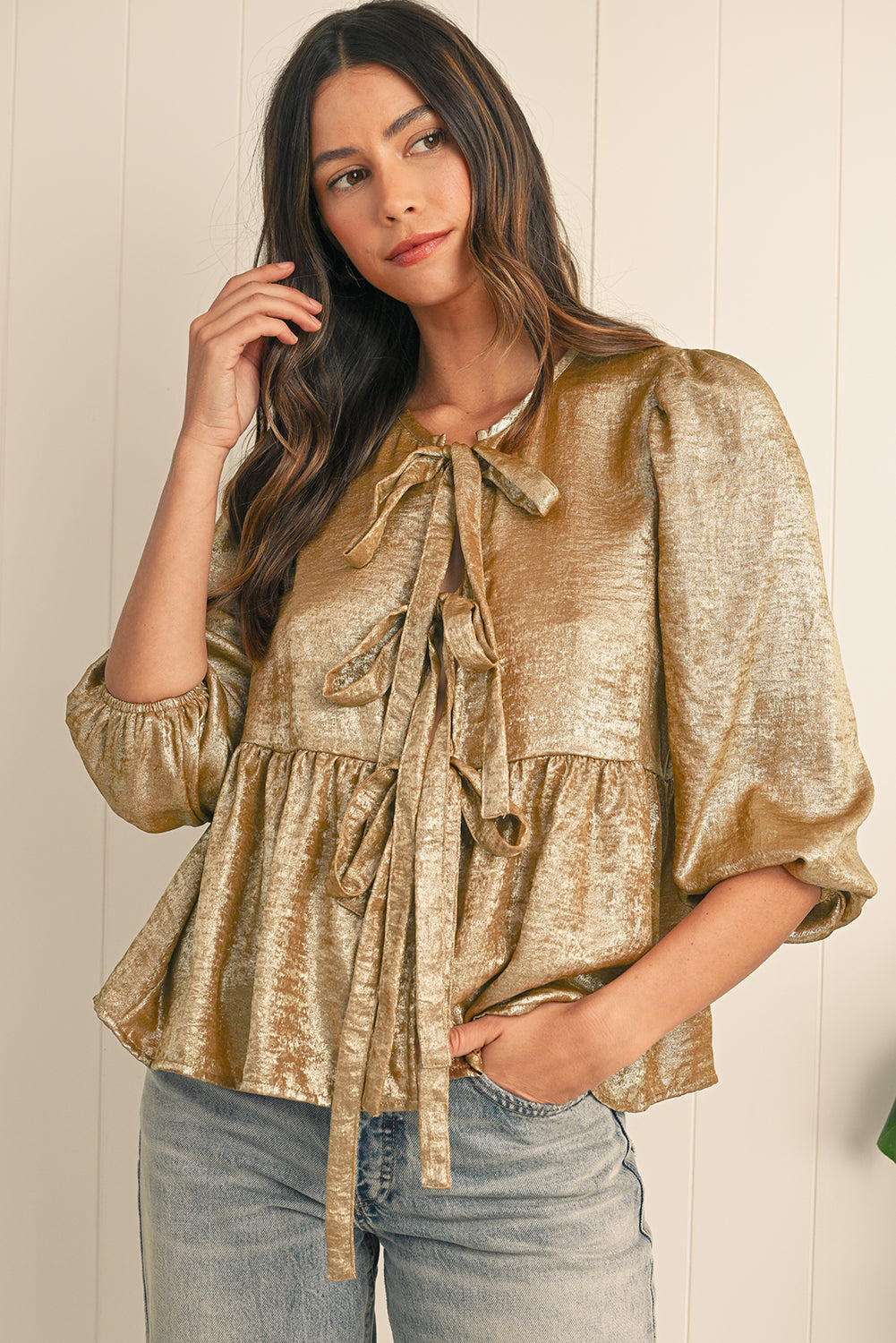 Woman wearing a gold metallic blouse with a white background