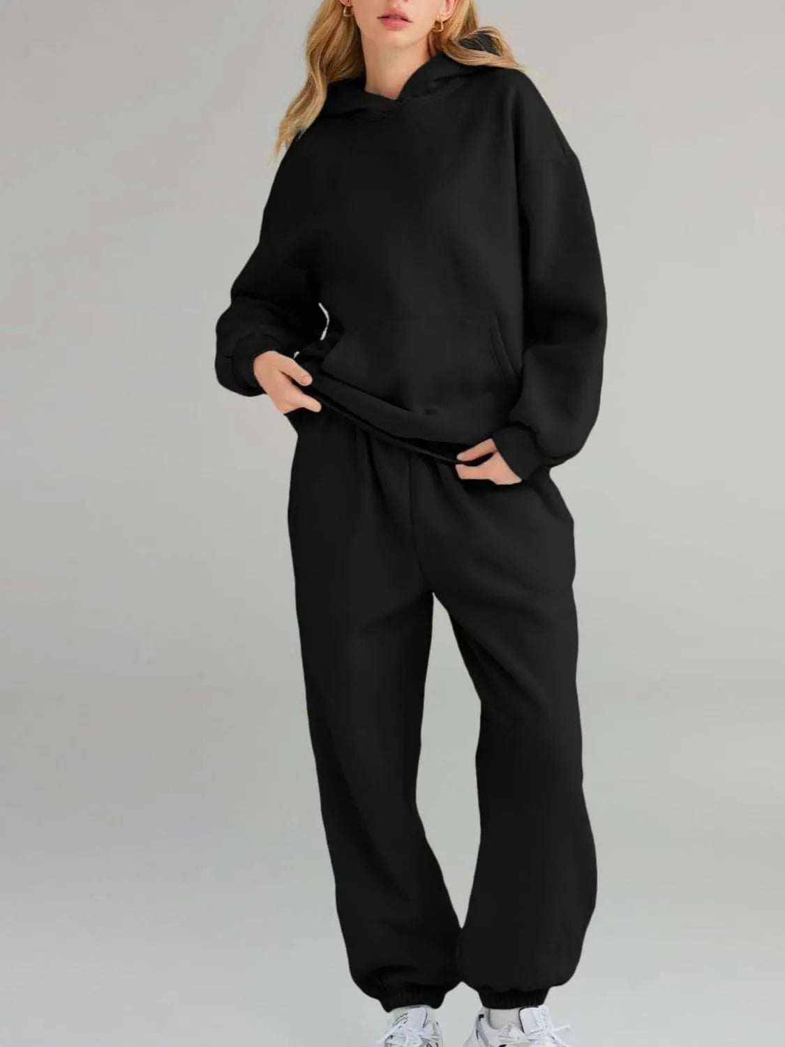 Person wearing a black tracksuit on a gray background