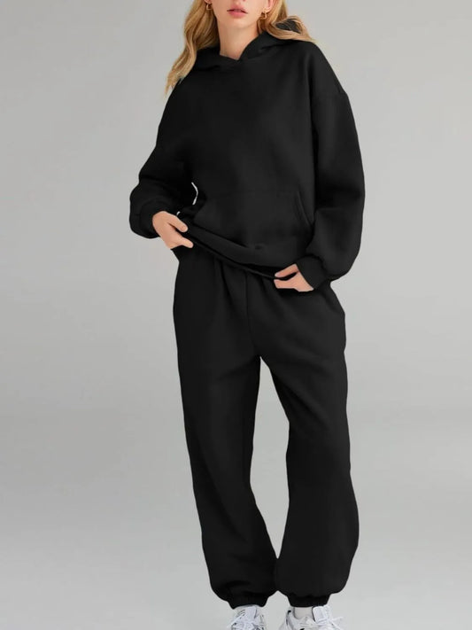 Person wearing a black tracksuit on a gray background
