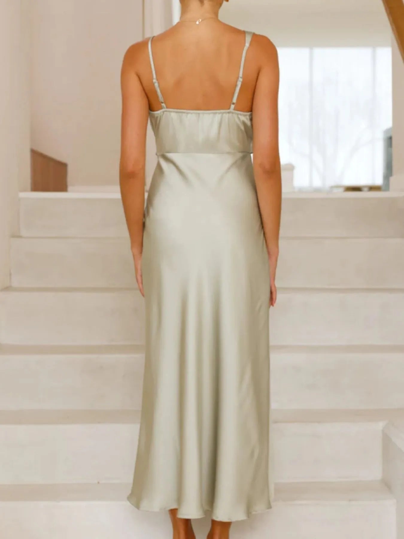 Woman wearing a light green dress standing on a staircase.