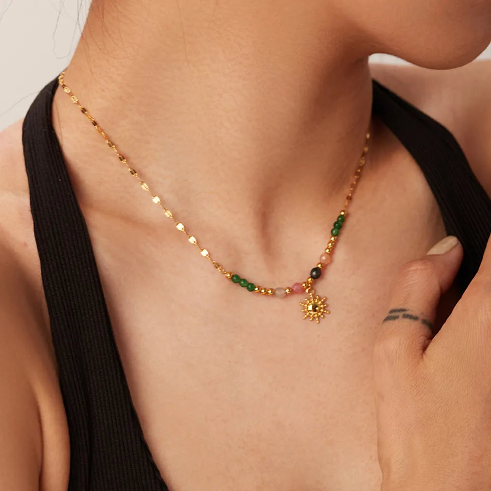 Necklace with colorful beads and a sun pendant worn by a person.