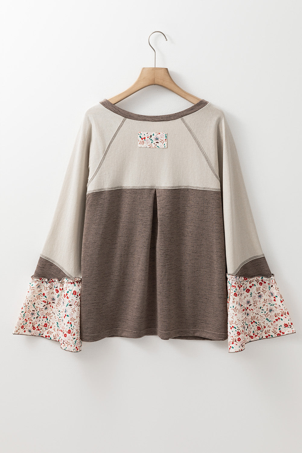Beige and brown dress with floral cuffs on a hanger against a white background