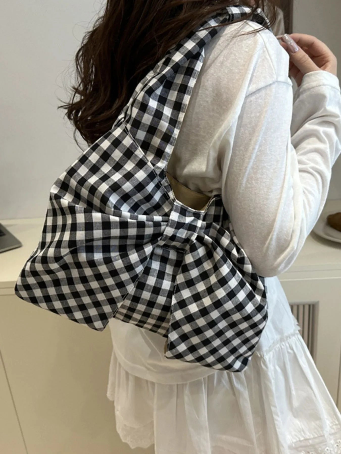 Person wearing a black and white checkered garment over a white long-sleeve shirt.