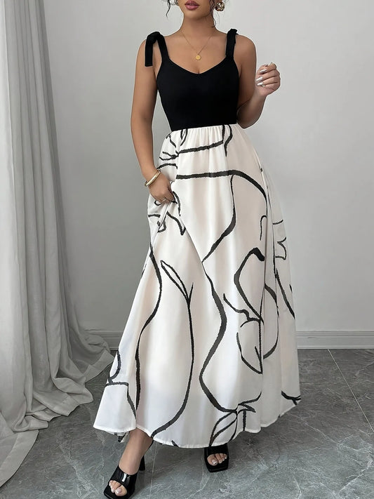 Woman wearing a black top and white skirt with black abstract patterns against a gray curtain background.