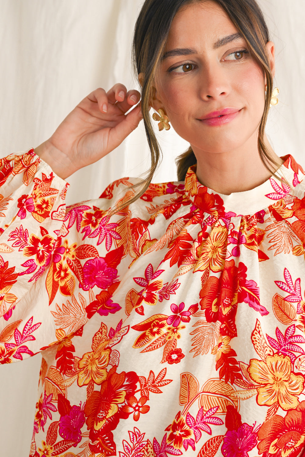 Woman wearing a floral blouse with orange and pink flowers on a white background