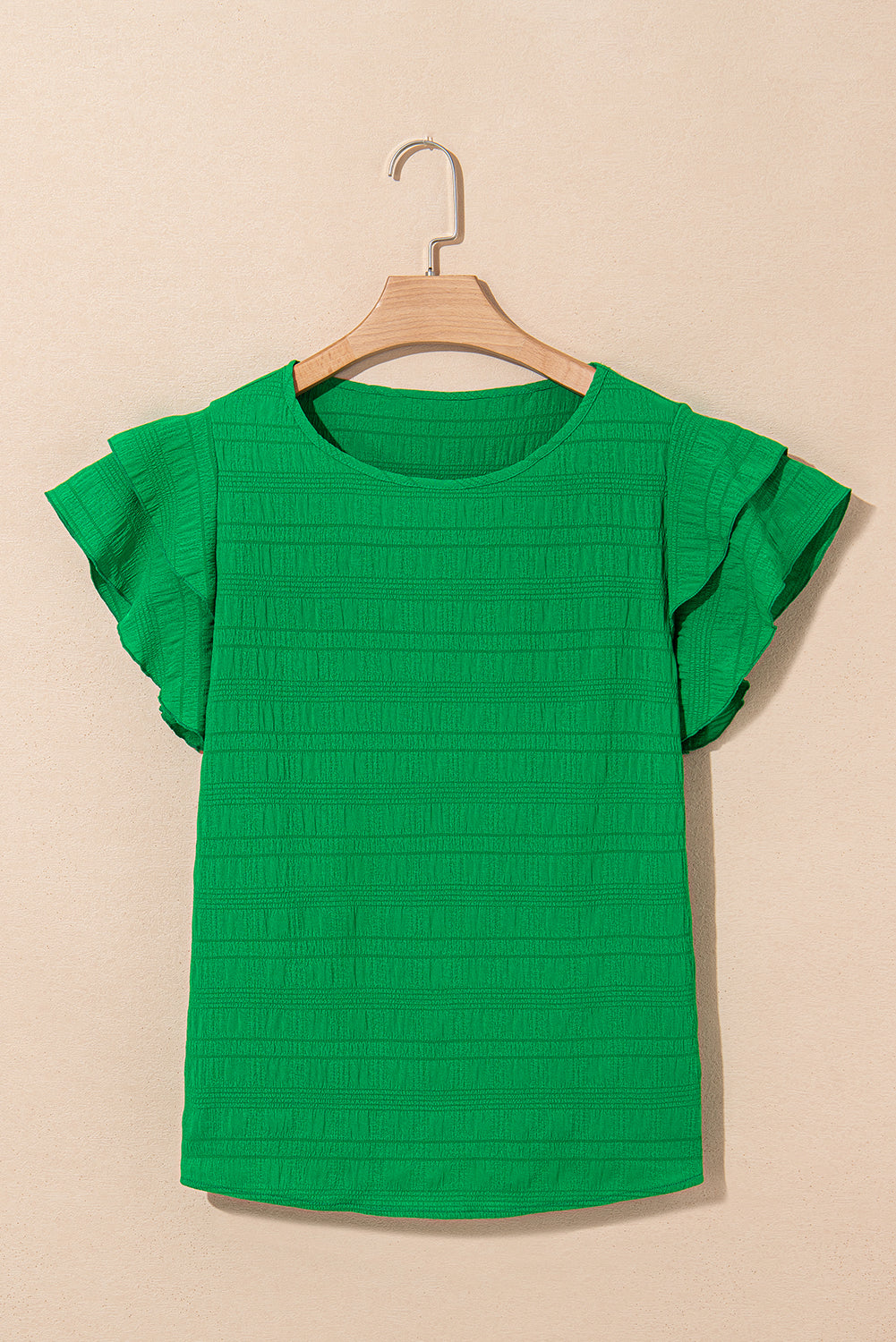 Green blouse with ruffled sleeves on a beige background