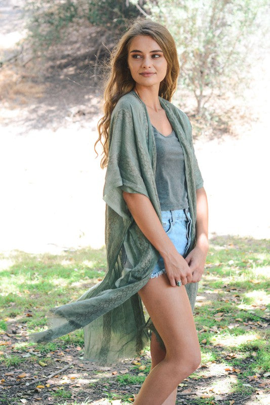 Woman wearing a green kimono-style garment in a natural setting