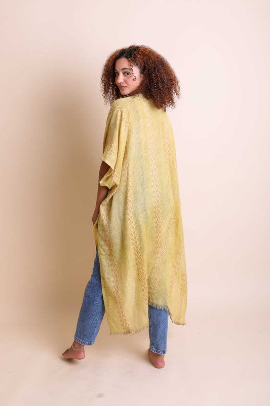 Woman wearing a yellow patterned shawl over a blue outfit on a beige background