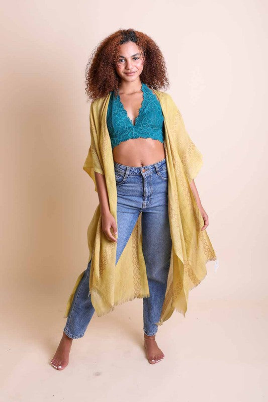 Woman wearing a teal top and yellow kimono over a beige background